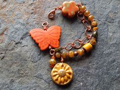 "Butterfly bracelet multi strand bracelet woodland fantasy sunny fall meadow statement bracelet indie boho orange and yellow butterflies This lovely boho butterfly bracelet features a big orange stone carved butterfly, a golden yellow polymer clay sunshine, or sunflower (handmade by moi and a ceramic multicolored flower. I've comprised one strand of pretty czech picasso glass beads interspersed with a vintage yellow chevron glass bead, unakite coins, and copper and carnelian accents. I've also a Bohemian Butterfly Jewelry For Festivals, Handmade Orange Bohemian Bracelets, Bohemian Butterfly Jewelry, Bohemian Orange Bracelet, Bohemian Butterfly Bracelets As Gift, Bohemian Butterfly Bracelet Gift, Bohemian Butterfly Bracelet, Fall Meadow, Boho Orange