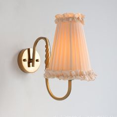 a lamp that is on the wall next to a light fixture with a white shade