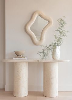 two white vases sitting next to each other in front of a wall mounted mirror