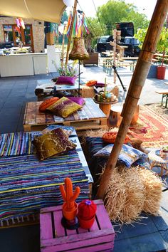 an outdoor seating area with colorful pillows and rugs on the ground next to a palm tree