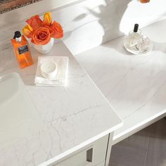 a bathroom vanity with white marble counter top and flowers in vases on the sink