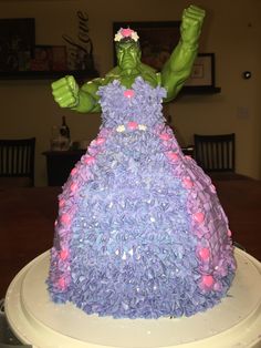 there is a cake made to look like a woman in a purple dress with flowers on her head