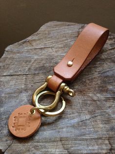 a brown leather keychain sitting on top of a piece of wood with a metal ring