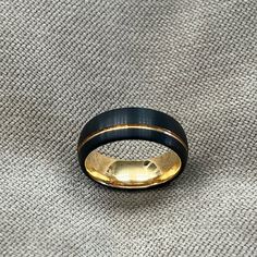 a black and gold ring sitting on top of a gray cloth