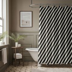 a black and white striped shower curtain hanging in a bathroom next to a bathtub