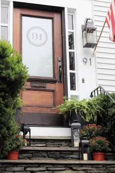 the front door of a house with potted plants on the steps