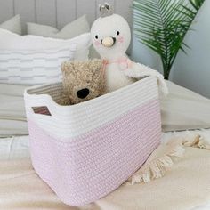 a stuffed animal sitting in a basket on top of a bed next to a teddy bear