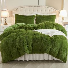 a bed covered in green fluffy blankets and pillows