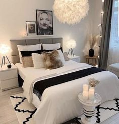 a white bedroom with black and white decor, candles and pictures on the wall above the bed