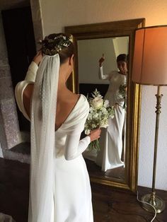 a woman in a wedding dress looking at herself in the mirror