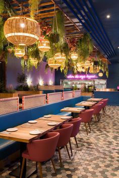 a restaurant with blue booths and plants hanging from the ceiling over the dining table area