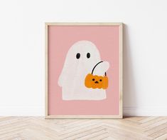 a white ghost holding an orange pumpkin in its mouth on a pink background with chevron herringbones