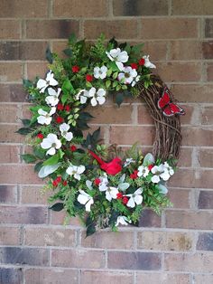 a wreath with white and red flowers hanging on a brick wall