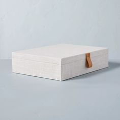 a white box sitting on top of a gray table next to a brown leather handle