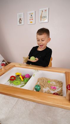 a young boy sitting at a table with food in front of him and eating it