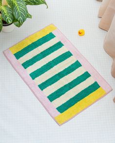 a green and yellow striped rug next to a potted plant