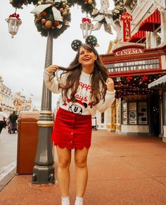 a woman standing in front of a christmas light pole with mickey mouse ears on her head