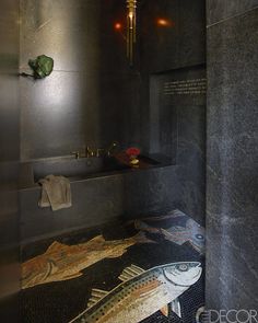 a bathroom with black walls and flooring has fish painted on the shower stall wall