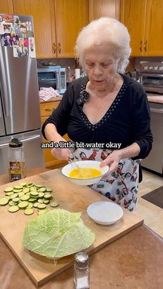 an older woman is preparing food in the kitchen with vegetables on the counter and plates