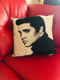 a red couch with a black and white elvis presley pillow sitting on top of it