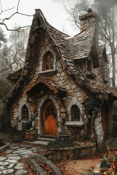 a small stone house with a wooden door and windows in the middle of a forest