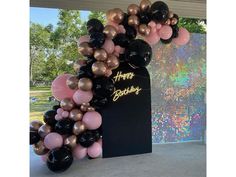 a black and gold balloon arch with happy birthday written on the front, surrounded by balloons