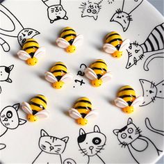 small yellow and black candy candies on a white plate with cats and kittens drawn on it