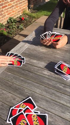 playing cards on a wooden table with someone reaching for them