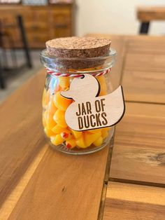 a jar filled with yellow candies sitting on top of a wooden table