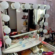 a mirror with balloons hanging from it in front of a table full of makeup and other items