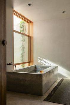 a bath tub sitting in the middle of a bathroom next to a wooden door and window