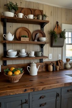 the kitchen counter is covered with dishes and cups, along with fruit on it's shelf