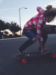 a woman riding a skateboard down the middle of a street