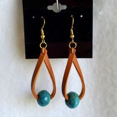 a pair of earrings with turquoise beads hanging from them