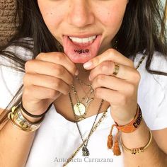 a woman with her tongue hanging out and wearing bracelets, necklaces and rings