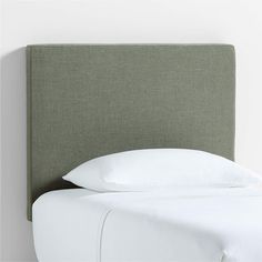 an upholstered headboard with white pillows and linens on the bottom half