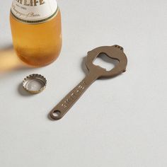 a bottle opener sitting on top of a table next to a bottle and a corkscrew