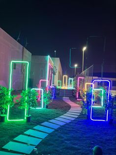 an illuminated pathway in the middle of a grassy area next to a building at night