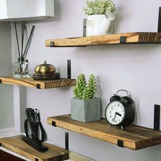 two wooden shelves with plants, an alarm clock and other decorative items on them in a living room