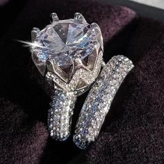 a diamond ring sitting on top of a purple velvet cushioned surface with diamonds surrounding it