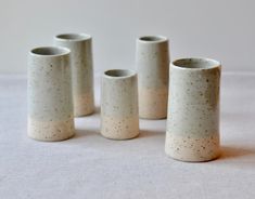 four white vases sitting on top of a table