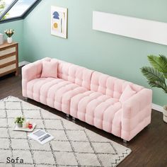 a pink couch sitting on top of a wooden floor next to a white and black rug