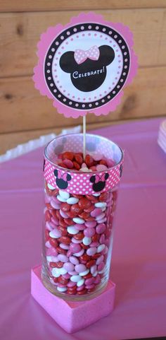 a cup filled with pink and white candies on top of a purple table cloth