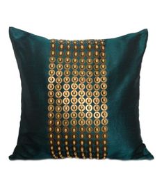 a green and gold pillow with circles on the front, sitting on a white surface