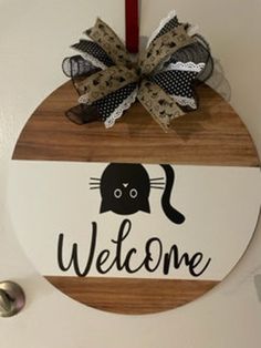 a welcome sign hanging on the front door with a red candle and some ribbon around it