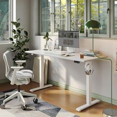 a white desk with a computer on top of it next to a chair and potted plant