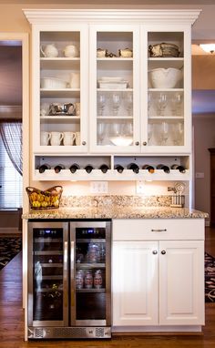 a kitchen with white cabinets and stainless steel refrigerator freezer combo in the center, filled with dishes