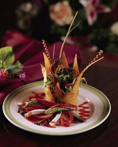 a plate with food on it sitting on a table next to some flowers and napkins