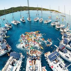 an aerial view of many boats in the water with people on them and one boat is surrounded by smaller boats