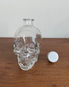 a glass bottle with a skull face on it and a small white object next to it